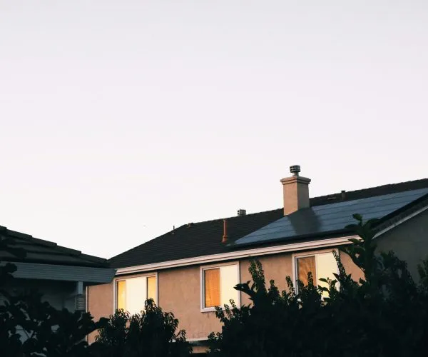 House at dusk with glowing windows and solar panels installed on the roof